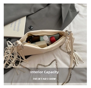 Spacious interior of beige pleated baguette bag showing lipstick and chain details