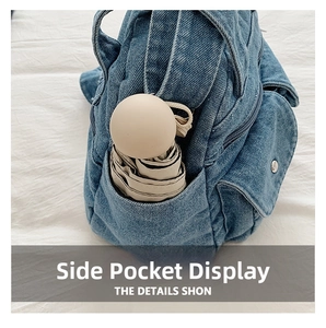 Detail of side pocket on denim crossbody bag showing storage for a folding umbrella