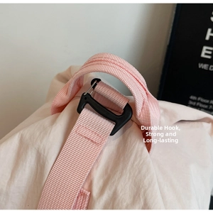 Close-up of a pink nylon strap featuring a durable black buckle on a canvas backpack