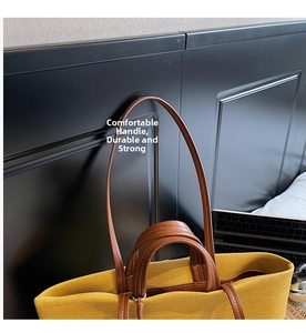 Detail of yellow canvas tote with brown leather handles and white contrast stitching