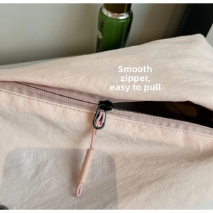 Detailed close-up of smooth zipper with black pull and pink canvas fabric on the handbag