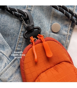 Detail of orange checkered mini bag with dual zippers and durable ripstop fabric