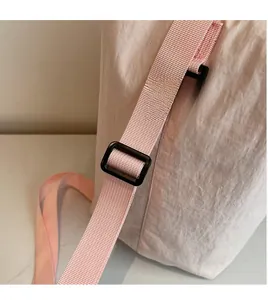 Detail of adjustable pink canvas bag strap with smooth texture and plastic buckle