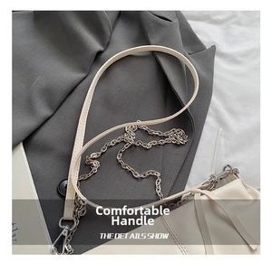 Detail of cream pleated baguette bag with silver chain strap and leather handle