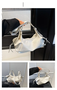 Détail du sac blanc en cuir brillant plissé avec pompon latéral et bandoulière réglable
