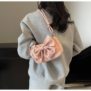 Detailed view of pink bow shoulder bag with pearl metal chain and velvet texture