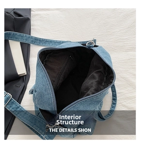 Internal view of blue denim crossbody bag featuring black lining and zipper pocket