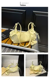 Détail du sac en cuir jaune crème brillant avec œillets métalliques et cordons
