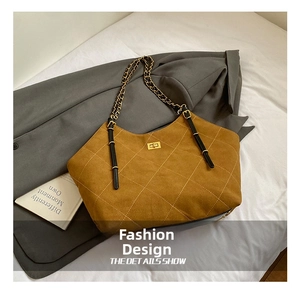 Close-up of brown quilted suede tote bag featuring gold clasp and metal chain strap