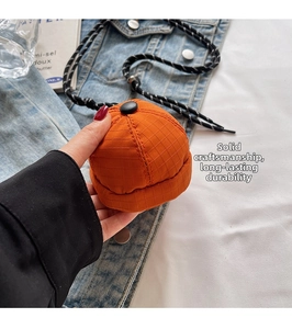 Detailed close-up of a mini orange hat-shaped fabric pouch with fine textured patterns