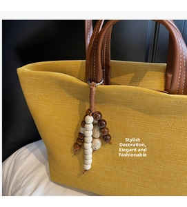 Ethnic style beaded charm with brown woven cord on a yellow textured canvas tote bag