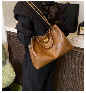 Detail of quilted dark brown tote with gold chain strap and metallic twist lock closure