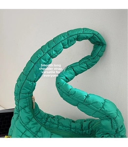 Detailed view of wide nylon shoulder strap and green quilted texture on cloud bag