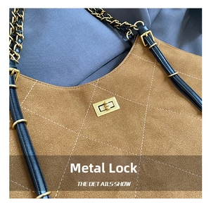 Detailed close-up of the vintage golden hardware lock on a brown quilted suede bag