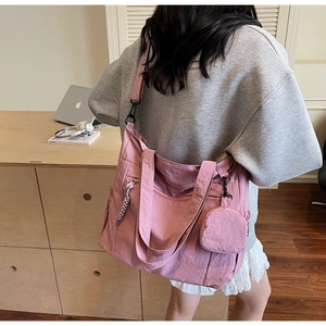 Detail of pink nylon tote bag featuring adjustable wide strap and mini round coin purse