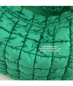 Detail of green quilted nylon fabric and seamless zipper on a lightweight cloud bag