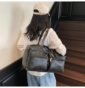 Detail of black PU leather travel tote showing dual front zipper pockets and texture
