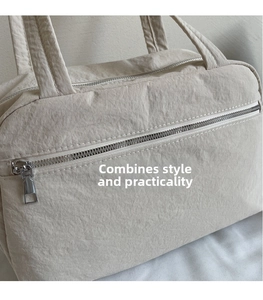 Detail of cream canvas tote showing textured fabric and silver metal zipper pocket