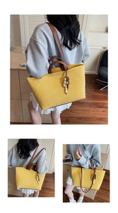Detail of yellow canvas tote bag featuring brown leather straps and beaded tassel charm