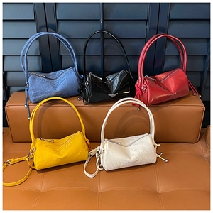 Detailed macro view showing five colors of textured leather pillow bags with metal chains