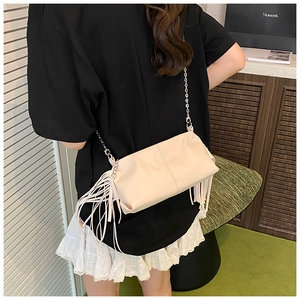 Detail shot of a cream fringe shoulder bag with silver metal chain on a model