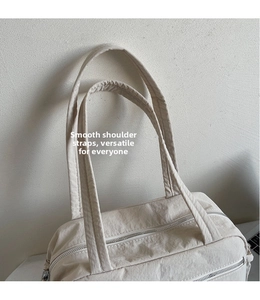 Detail of a beige canvas tote bag with smooth shoulder straps and a durable metal zipper closure