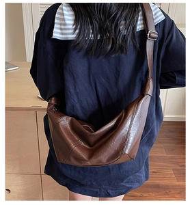 Rear view of model wearing a brown vintage crossbody hobo bag with adjustable strap