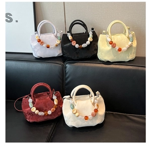 Gros plan de sacs seaux en velours plissés avec chaînes de perles en acrylique colorées