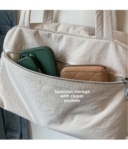 Close-up of cream nylon tote bag featuring front zipper pocket and spacious interior storage