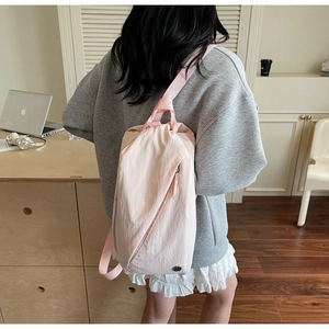 Detailed back view of pink nylon crossbody bag with adjustable wide strap on a person