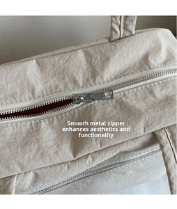 Detail of smooth silver metal zipper puller on beige canvas tote bag surface