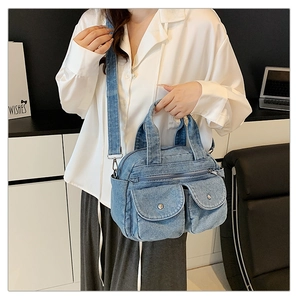 Detail of vintage denim crossbody bag with silver buckles and multi-pocket design on model