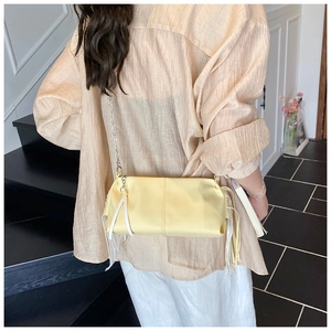 Detail of yellow soft leather crossbody bag with long tassels and silver chain strap