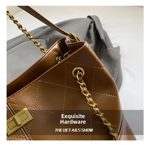 Close-up of golden metal lock and chain strap on brown quilted leather shoulder bag