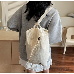 Close-up of a cream-colored drawstring canvas backpack with natural wrinkled texture