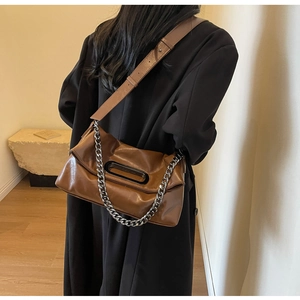 Braune weiche Ledertasche mit silberner Kette und breitem Schultergurt am Model