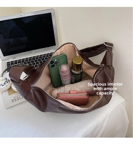 Intérieur spacieux du sac croissant marron foncé contenant téléphone et accessoires