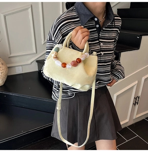 Détail du sac seau plissé avec chaîne en perles acryliques et finition en similicuir