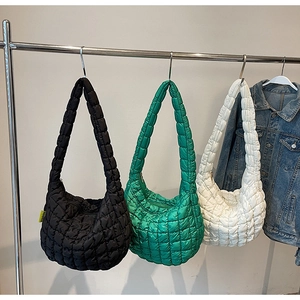 Three quilted puffy tote bags in black, green and white hanging on silver metal hangers