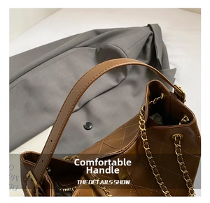Detail of brown quilted leather tote featuring golden chain strap and zipper closure