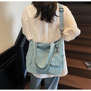 Light blue large canvas tote bag showing wide shoulder strap and round mini pouch detail