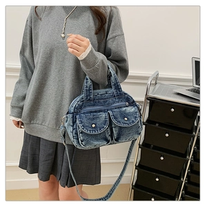 Detail of vintage denim crossbody bag with contrast pockets and metal buckle hardware