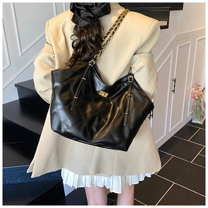 Close-up of black quilted leather tote bag with gold chain strap and metal rotary lock
