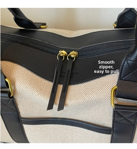 Detail view of smooth golden double zippers and premium leather trim on canvas travel bag
