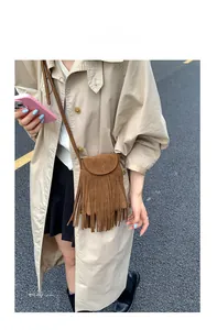 Sac bandoulière marron en daim avec franges porté par un mannequin en extérieur