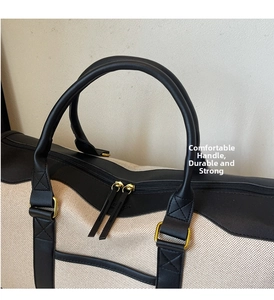 Detailed close-up of durable canvas travel bag with leather handles and gold metal zippers