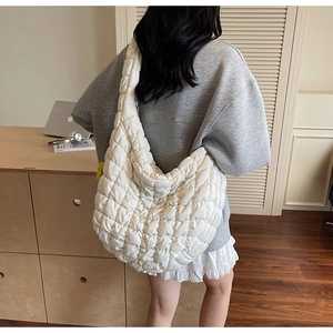 Detailed view of white quilted puffer bag with plush texture and wide shoulder strap