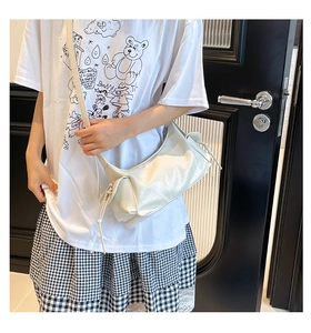 Détail du sac à bandoulière en cuir blanc brillant avec cordon de serrage porté