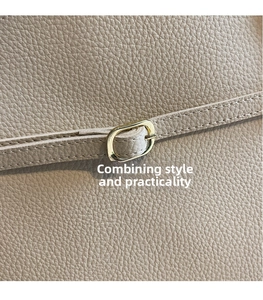 Close-up of beige lychee texture leather bag featuring an oval golden metal clasp