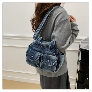 Detail of vintage denim crossbody bag with multiple front pockets and silver metal buttons